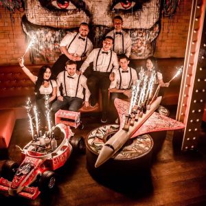 Staff with a model racing car and a model aeroplane at INK Bar